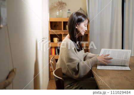 リビングのテーブルで読書する女性 111029484