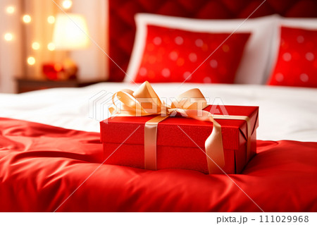 Red gift box with gold ribbon on bed decoration in hotel bedroom interior 111029968