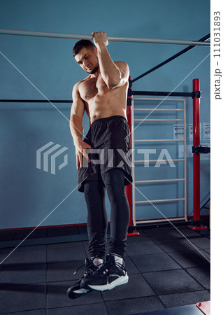 Strong, athletic young man with muscular, relief body training shirtless in gym, doing one arm pull ups. Strong, athletic young man with muscular, relief body training shirtless in gym, doing one arm pull ups. 111031893