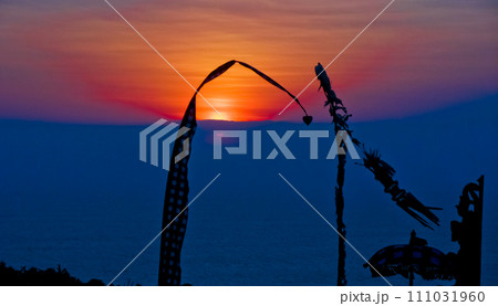 views of Penjor, Janur and Balinese temples with a beautiful sunset in the background 111031960