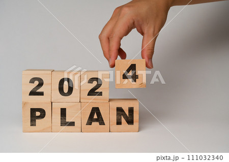 Hand placing wooden cube blocks with 2024 PLAN text on white background. Business vision and development concept 111032340