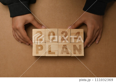 Hand arranging wooden cubes with 2024 PLAN text on brown background. Business plan concept Hand arranging wooden cubes with 2024 PLAN text on brown background. Business plan concept 111032369