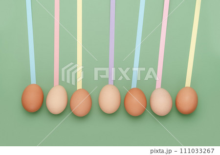 Row of different shade eggs with fun leading geometric lines on green background. Copy space simple pastel rustic background for traditional Easter holiday card Row of different shade eggs with fun leading geometric lines on green background. Copy space simple pastel rustic background for traditional Easter holiday card 111033267