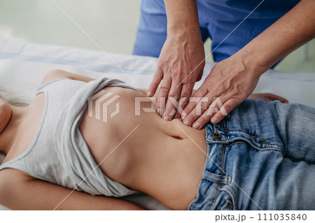 Close up of doctor palpating girl's abdomen, hands and steady pressure on belly. Concept of preventive health care for children. 111035840