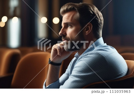 Man sits on chair, holds chin with hand, 111035963