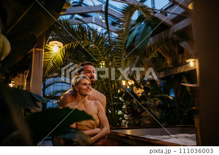 Beautiful couple standing in hotel greenhouse, enjoying romantic wellness weekend in spa. Concept of Valentine's Day. Beautiful couple standing in hotel greenhouse, enjoying romantic wellness weekend in spa. Concept of Valentine's Day. 111036003