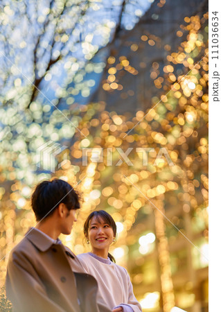 イルミネーションの街並みで、楽しげに男性と話す女性 イルミネーションの街並みで、楽しげに男性と話す女性 111036634