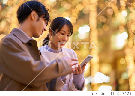 楽しげにスマートフォンを操作する女性と男性 111037423