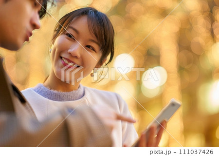 楽しげにスマートフォンを操作する女性と男性 111037426