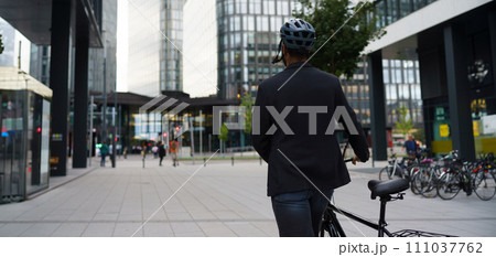 Rear view of city bike commuter leaving work on bicycle after long work day. Banner with copy space. 111037762