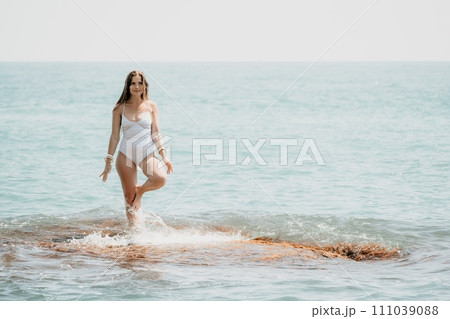 Woman sea yoga. Back view of free calm happy satisfied woman with long hair standing on top rock with yoga position against of sky by the sea. Healthy lifestyle outdoors in nature, fitness concept 111039088