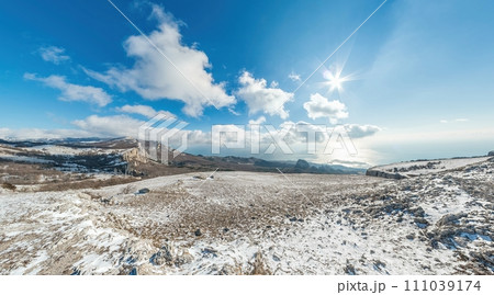 Winter snow mountain panorama. panoramic aerial view above sea and snow covered frozen mountains with deep blue sky and a beautiful radiant sun. Cold weather and climate change 111039174