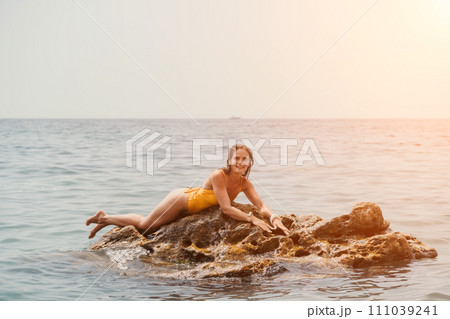 Woman travel sea. Happy tourist in hat enjoy taking picture outdoors for memories. Woman traveler posing on the beach at sea surrounded by volcanic mountains, sharing travel adventure journey 111039241