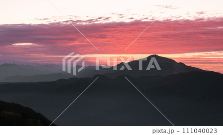 Silhouettes of mountains in golden sunset. Moving clouds in orange sky. Silhouettes of mountains in golden sunset. Moving clouds in orange sky. 111040023