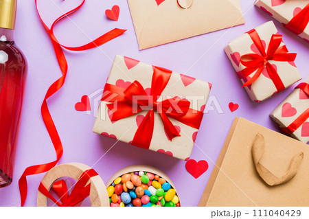 top view photo of st valentine day decor shopping, bag, wine, bottle, envelope, gift, box, candy and red heart on colored background with empty space. Frame background top view photo of st valentine day decor shopping, bag, wine, bottle, envelope, gift, box, candy and red heart on colored background with empty space. Frame background 111040429