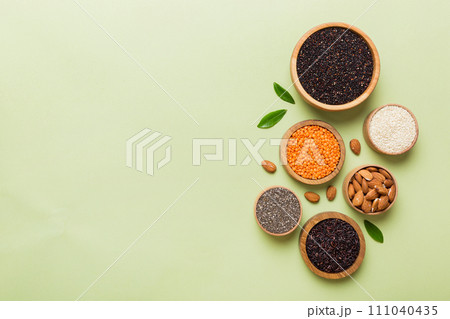 Various superfoods in smal bowl on colored background. Superfood as rice, chia, quinoa, lentils, nuts, sesame seeds, almonds. top view copy space Various superfoods in smal bowl on colored background. Superfood as rice, chia, quinoa, lentils, nuts, sesame seeds, almonds. top view copy space 111040435