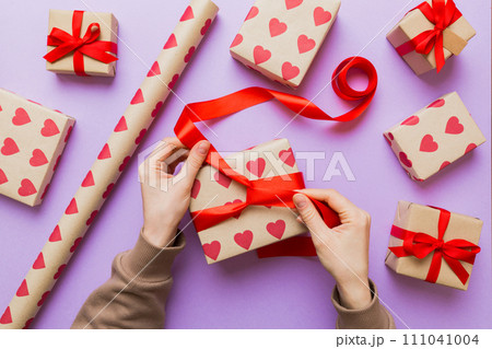Women hands pack gifts and make decorations for the holiday, top view. Birthday and valentine present 111041004