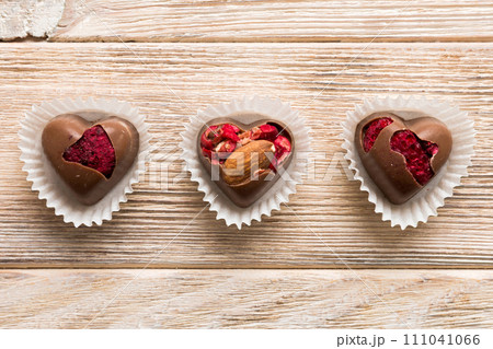 chocolate sweets in the form of a heart with fruits and nuts on a colored background. top view with space for text, holiday concept 111041066