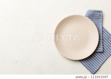 Top view on colored background empty round white plate on tablecloth for food. Empty dish on napkin with space for your design 111041097