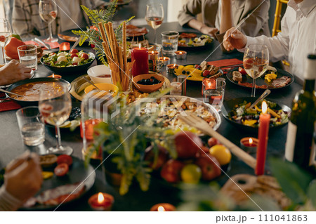 Cozy holiday table setting with different delicious food and beverages ready for friends home party Cozy holiday table setting with different delicious food and beverages ready for friends home party 111041863