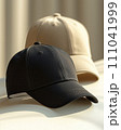 two baseball caps, one in black and the other in a light beige color. 111041999