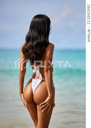 Beautiful asian girl in white bikini posing at the tropical beach 111042092