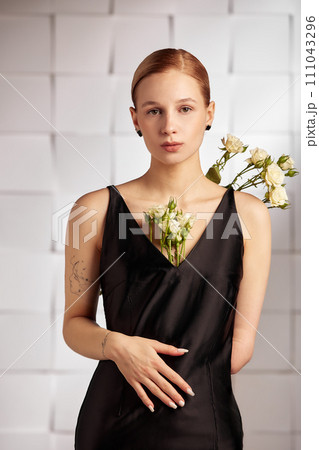 Beautiful young with special needs woman with flowers in her hand holding a flower, woman in black dress. Diversity handicap and flowers. Beautiful young with special needs woman with flowers in her hand holding a flower, woman in black dress. Diversity handicap and flowers. 111043296