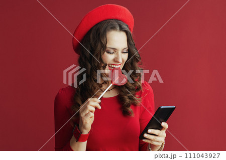 woman isolated on background with heart shaped candy using phone woman isolated on background with heart shaped candy using phone 111043927