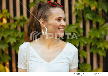 smiling young woman in white shirt near wooden wall 111044089