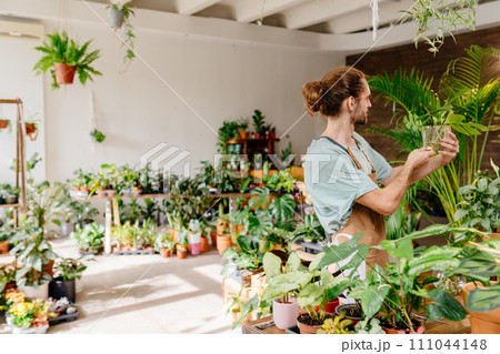 Caucasian male shop assistant working in indoor potted plant store, small business concept. Caucasian male shop assistant working in indoor potted plant store, small business concept. 111044148