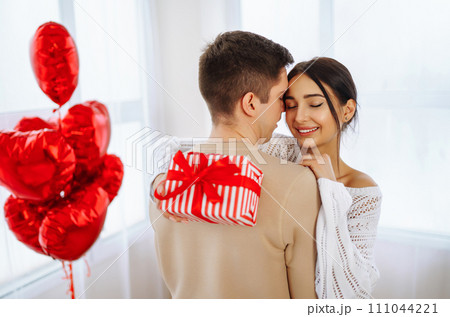 Young couple at home celebrating Valentine's Day. Exchange of gifts. Surprise and love concept. Young couple at home celebrating Valentine's Day. Exchange of gifts. Surprise and love concept. 111044221