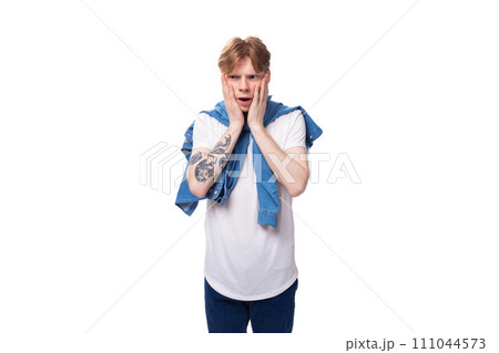young emotional handsome slender red-haired man with a tattoo on his arms is dressed in a stylish 111044573