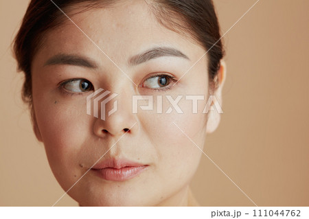 young asian woman looking sideway on beige background young asian woman looking sideway on beige background 111044762