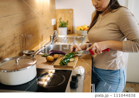 Beautiful young female cutting vegetables on kitchen at home. Home food concept 111044838