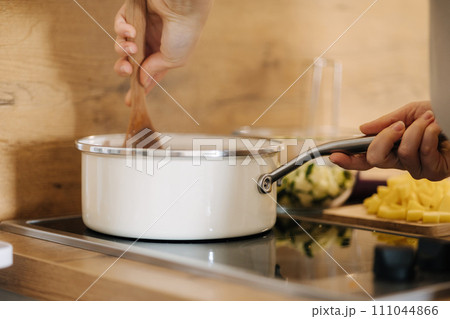 Side view of human hand stirs ingredients with a wooden spoon. Home made food concept. Kitchen 111044866