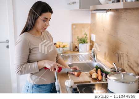 A young beautiful woman is preparing lunch in her kitchen at home. Vegan 111044869