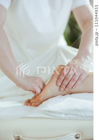 Massage therapist in massage cabinet massaging clients foot Massage therapist in massage cabinet massaging clients foot 111044933