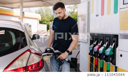 Handsome young man refueling car at gas station. Petrol concept. Side view Handsome young man refueling car at gas station. Petrol concept. Side view 111045084