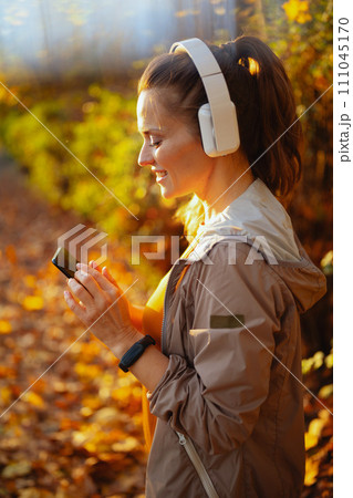 elegant woman in fitness clothes in park with headphones elegant woman in fitness clothes in park with headphones 111045170
