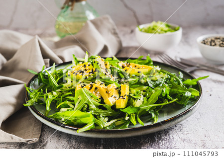 Vegetarian salad of arugula leaves, cucumber, avocado and sesame on a plate 111045793