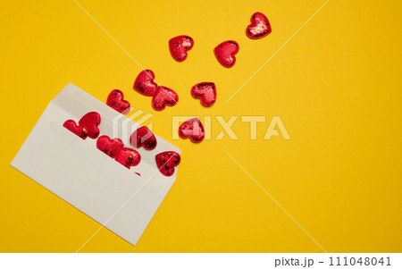 Rectangular white paper envelope and red hearts on a yellow background Rectangular white paper envelope and red hearts on a yellow background 111048041