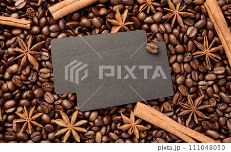 A black business card lies on scattered roasted coffee beans, space for an inscription A black business card lies on scattered roasted coffee beans, space for an inscription 111048050