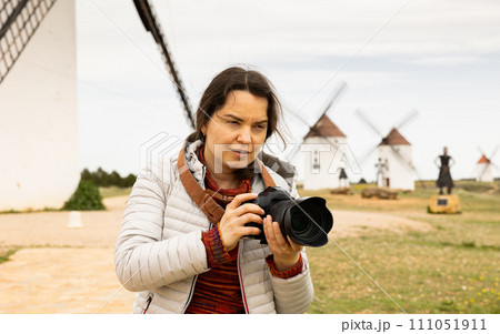 Woman tourist takes pictures of the windmills of Mota del cuervo. Spain Woman tourist takes pictures of the windmills of Mota del cuervo. Spain 111051911