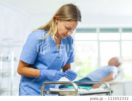 Concentrated woman doctor checking instruments for medical procedures 111052332