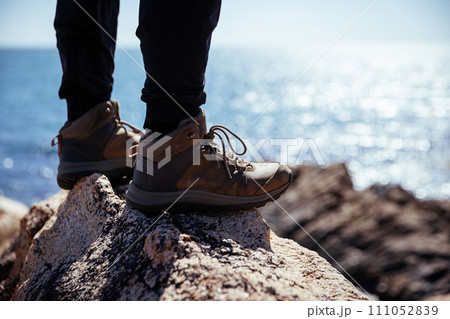 Hiker legs stand on seaside rock Hiker legs stand on seaside rock 111052839