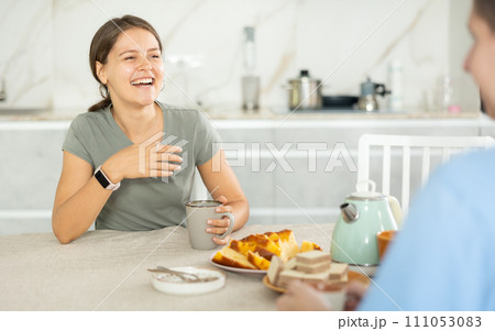 Cheerful girl in kitchen communicates with man over cup of tea 111053083