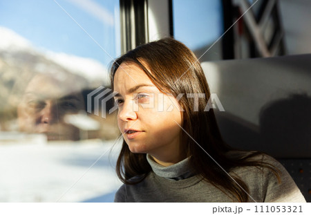 Woman looking at scenery outside window while traveling by train 111053321