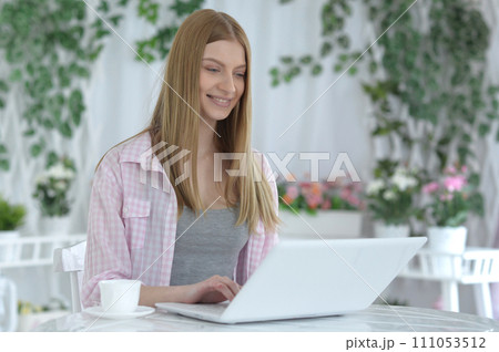 Portrait of young woman using laptop at home 111053512