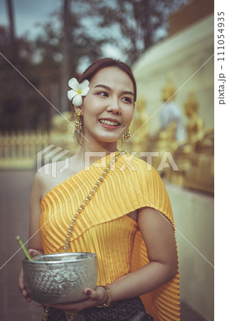 A beautiful Thai woman wearing a Thai traditional dress playing Songkran festival in the temple A beautiful Thai woman wearing a Thai traditional dress playing Songkran festival in the temple 111054935