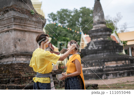 A beautiful Young Thai couple wearing Thai costumes playing in the water during Songkran in the temple 111055046
